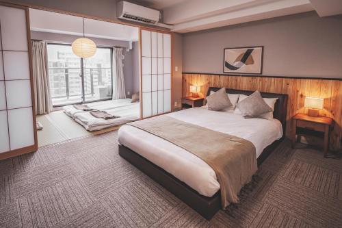 a bedroom with a large bed and a window at Chuan House Dotonbori in Osaka