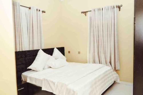 un letto bianco con cuscini bianchi in una camera da letto di Cityflats Apartment a Owerri