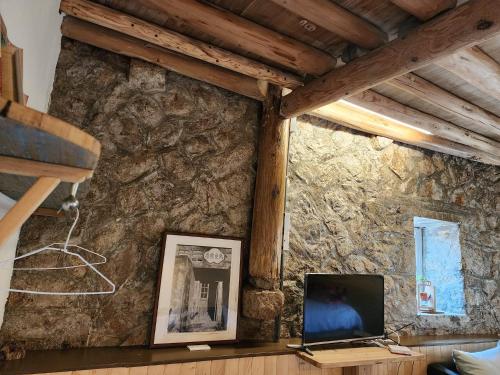 a living room with a stone wall with a television at Eternal Seaside House in Nangan