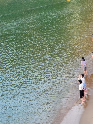 a group of people walking on the beach near the water at Eternal Seaside House in Nangan