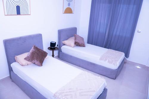 two beds in a room with blue curtains at Duplex La rose neuf et elegant in Sidi Bouzid
