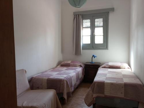 2 camas en una habitación con ventana y silla en Artemisa en Piriápolis