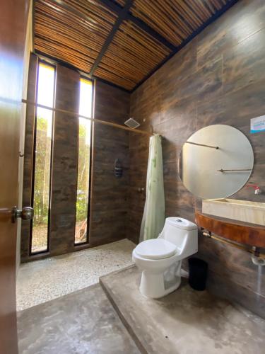 - une salle de bains avec toilettes dans une chambre dotée de murs en bois dans l'établissement Bio Casa Inusual, à Girardot