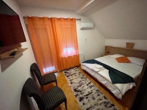 a small bedroom with a bed and two chairs at Madigan's Hotel in Kosovo Polje