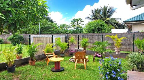 a yard with chairs and a table and plants at TAHITI - Motu Nono Beach View in Atihiva