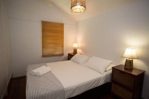 een slaapkamer met een bed, 2 lampen en een raam bij Bev's on the Beach - Absolute Beachfront Cottage in Mission Beach