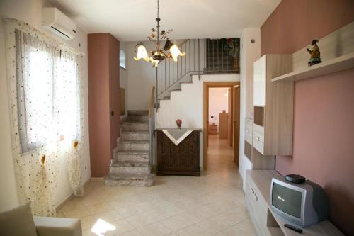 uma sala de estar com uma escada e uma televisão em A Casitta a pochi km da Taormina em Calatabiano