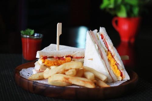 a sandwich and french fries on a wooden plate at Star Hotel Chiang Mai - SHA Extra Pus in Chiang Mai