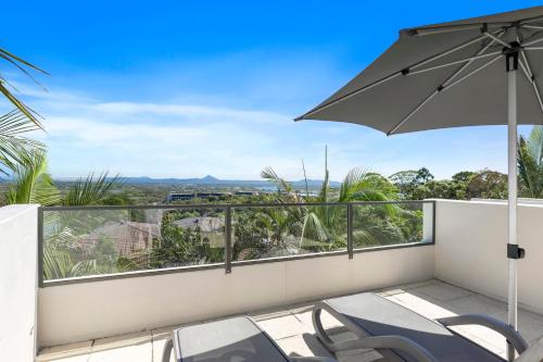 a balcony with chairs and an umbrella at Noosa Blue Resort in Noosa Heads
