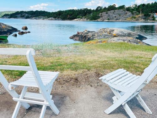 two white chairs and a table next to the water at 6 person holiday home in HENÅN-By Traum in Henån