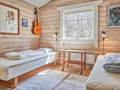 a room with wooden walls with a bed and a guitar at Holiday home Rønne XXII in Rønne