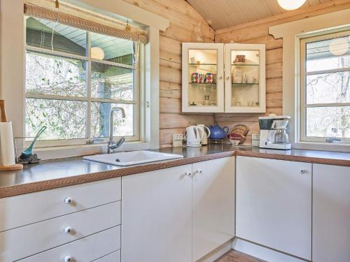 a kitchen with white cabinets and a sink and two windows at Holiday home Rønne XXII in Rønne