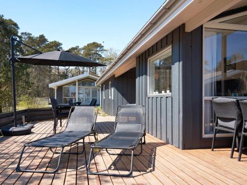 a deck with chairs and an umbrella on a house at 8 person holiday home in Nexø in Neksø