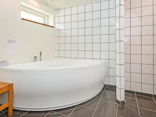 La salle de bains est pourvue d'une baignoire et de carrelage blanc. dans l'établissement Holiday home Ebeltoft CCXXII, à Ebeltoft