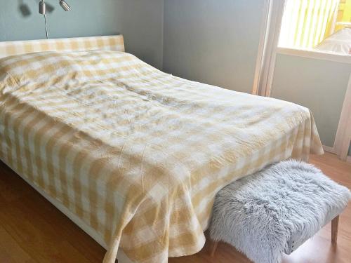 ein Bett mit einer gelben und weißen Decke und einem Stuhl in der Unterkunft Holiday home FÄRENTUNA IV 