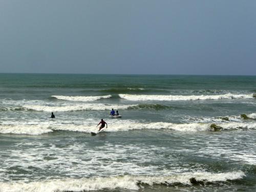 a group of people riding waves in the ocean at Ankobra Beach Resort in Axim