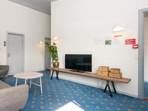 a living room with a desk with a tv and a chair at Apartment in Holiday park- shared kitchen in Ulfborg