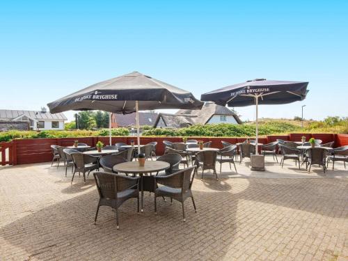 an outdoor patio with tables and chairs and umbrellas at Apartment in Holiday park- shared kitchen in Ulfborg