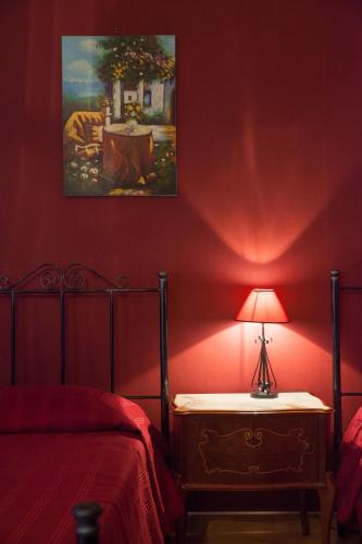 a red bedroom with a bed and a lamp on a table at Il Cavaliere in Trapani
