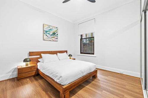 a white bedroom with a bed and a window at Kings4 Self Catering in Sydney