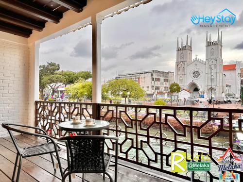 a table and chairs on a balcony with a view of a church at Wayfarer Guest House Jonker Street Melaka By Heystay Management in Melaka