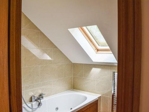 Salen的住宿－Frasers Cottage，带浴缸和天窗的浴室