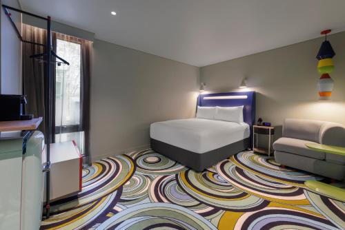 a bedroom with a bed and a colorful carpet at Adge Hotel and Residences in Sydney