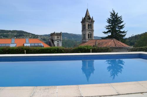 a swimming pool in front of a building with a clock tower at Casa Quinta da Calçada Douro in Cinfães