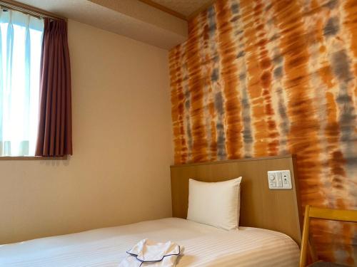 a room with a bed and a window and a wall at SAKURA SKY HOTEL KASHIWA(桜スカイホテル柏) in Kashiwa