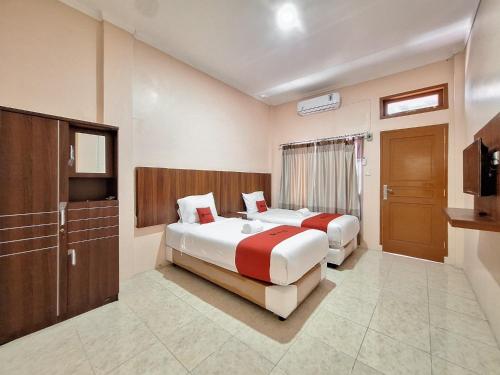 um quarto de hotel com duas camas e uma televisão em RedDoorz Syariah near Pasar Raya Padang em Padang