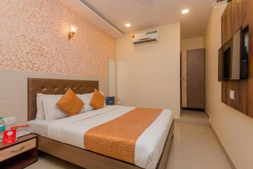 Hotel Golden Nest Near Chhatrapati Shivaji International Airport في مومباي: غرفة نوم بسرير وتلفزيون بشاشة مسطحة
