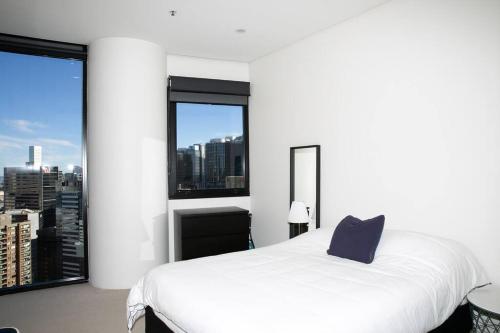 a white bed with a blue pillow in a room with windows at Sydney Sky high Self-Catering in Sydney