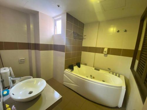 a bathroom with a tub and a toilet and a sink at Junikastay BLagoon Melaka in Melaka