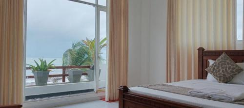 a bedroom with a bed and a large window at Bivon Reach By Travel Corners in Uswetakeiyawa