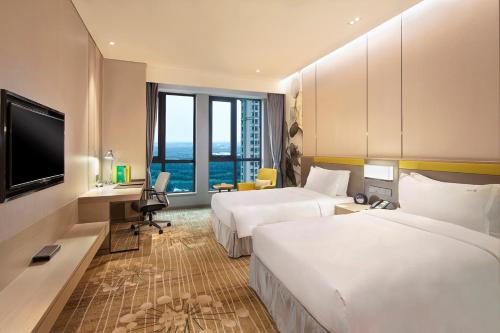 um quarto de hotel com duas camas e uma televisão de ecrã plano em Holiday Inn Tianjin Wuqing, an IHG Hotel em Wuqing