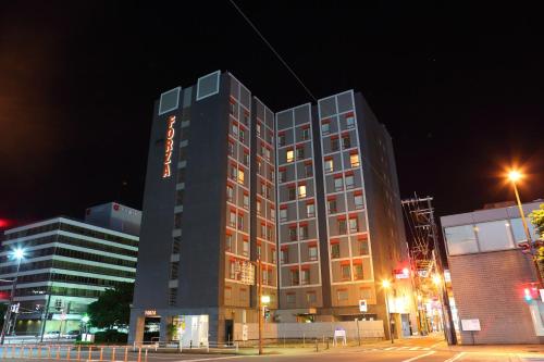 un edificio alto con un cartel en él por la noche en Hotel Forza Oita en Oita