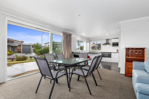 a dining room with a glass table and chairs at Shores Getaway - One Tree Point Holiday Home in One Tree Point