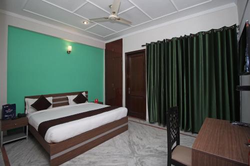um quarto com uma cama, cortinas verdes e uma mesa em OYO Flagship 9075 Petals Inn em Noida