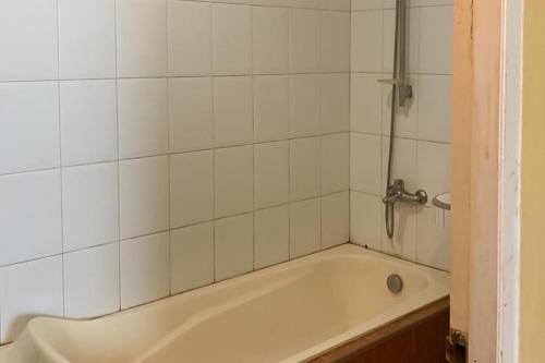 a bath tub in a bathroom with white tiles at Hotel Laut Jaya Tanjung Pinang RedPartner in Tanjung Pinang