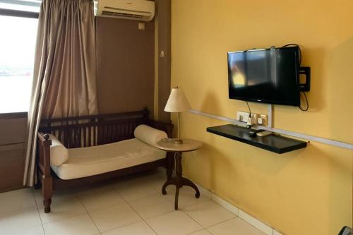 a room with a tv and a chair and a table at Hotel Laut Jaya Tanjung Pinang RedPartner in Tanjung Pinang 