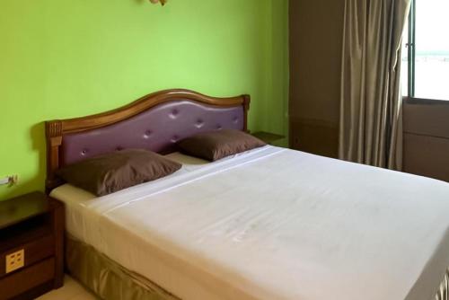 Cama en habitación con pared verde en Hotel Laut Jaya Tanjung Pinang RedPartner en Tanjung Pinang