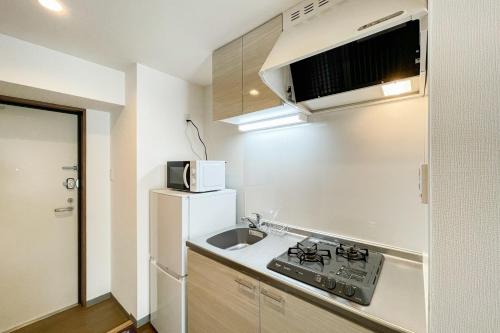 a small kitchen with a sink and a microwave at Shin-Umeda Central Hills in Osaka