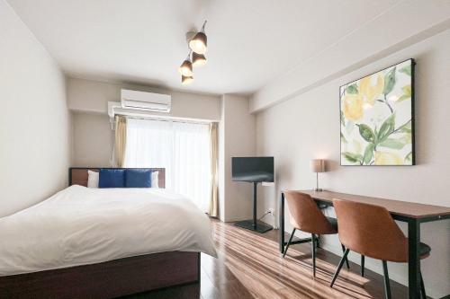 a bedroom with a bed and a desk with chairs at Shin-Umeda Central Hills in Osaka