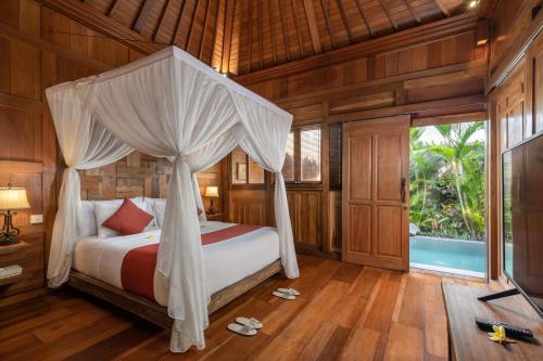 a bedroom with a bed with a canopy at Candy Villa by Pramana Villas in Ubud