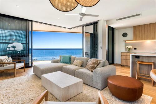 a living room with a couch and a table at Absolute Beachfront Luxury Apartment in Coolum Beach