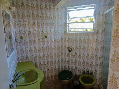 La salle de bains est pourvue d'un lavabo, de toilettes et d'une fenêtre. dans l'établissement Apartamento Edifício Arpoador (Praias Asturias-Tombo), à Guarujá