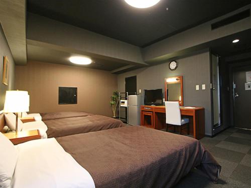 a hotel room with two beds and a desk with a computer at HOTEL LiVEMAX BUDGET Yokohama Tsurumi in Yokohama