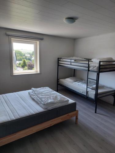 a bedroom with two bunk beds and a window at Al'fagne de boca in Bertogne