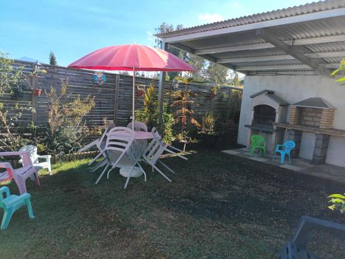 a patio with a table and chairs and an umbrella at LOCATIONS VERT EDEN in La Plaine des Cafres