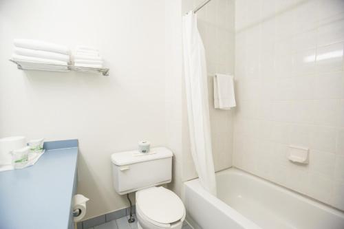 uma casa de banho branca com um WC e um chuveiro em Motel Vaudreuil em Vaudreuil-Dorion